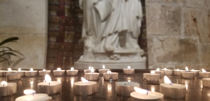 Prayer votives lit under the statue of Anne and Mary.